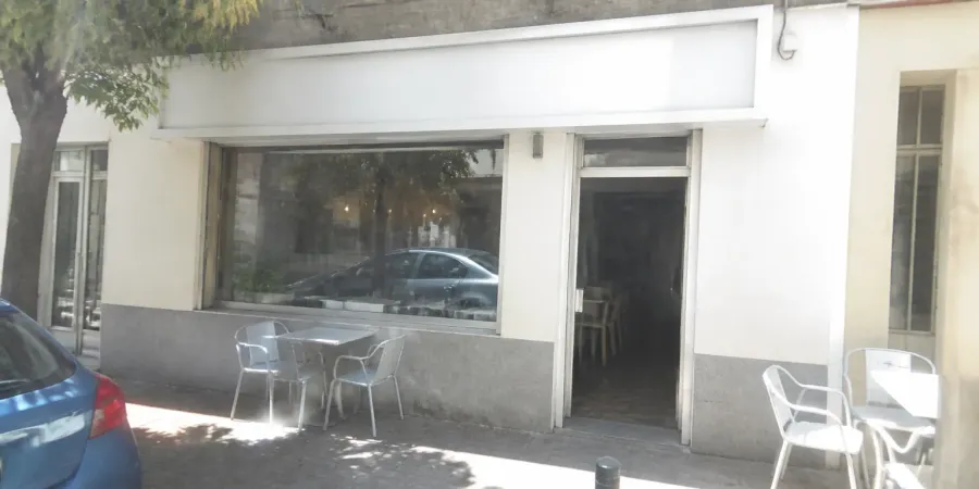 La foto que mandó el cliente: la fachada del local hecha con el móvil, con luz dura, colores lavados y un coche aparcado delante